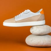 Thumbnail of a pair of white sneakers placed on stones, highlighting the sole and design details.